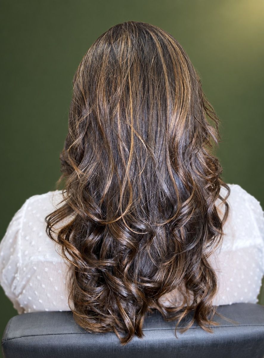 Cabelo castanho ondulado com mechas iluminadas, visto de costas